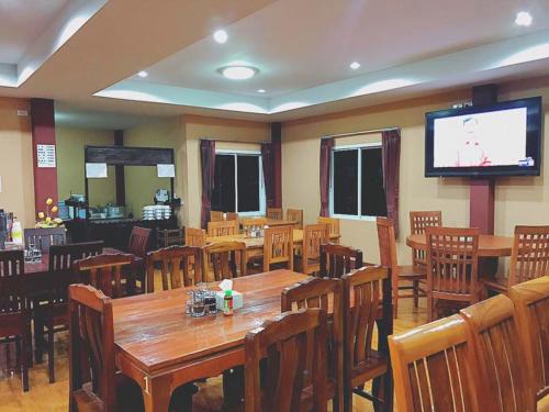 a restaurant with wooden tables and chairs and a flat screen tv at Khwanruen Fishing Resort in Ban Chang