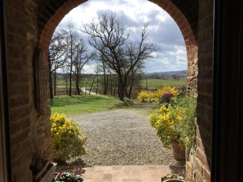 an archway leading into a garden with trees and flowers at La Berchiera in Ciggiano