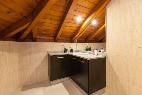 a bathroom with two sinks and a wooden ceiling at Casa dos Colados in Fafe