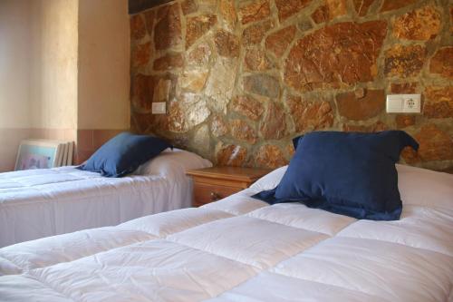 a bedroom with two beds and a stone wall at Casa Rural Sierra De Coripe in Coripe