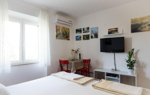 Habitación blanca con TV y mesa con sillas. en Gravosa Studios, en Dubrovnik