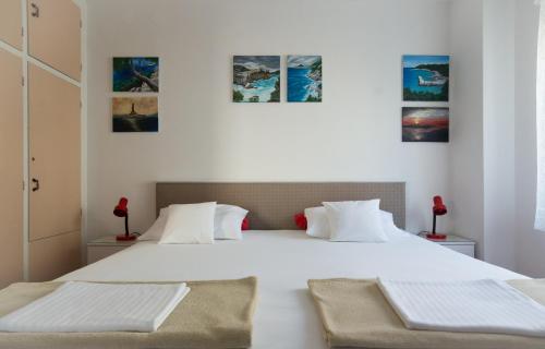 a white bedroom with two beds and paintings on the wall at Gravosa Studios in Dubrovnik