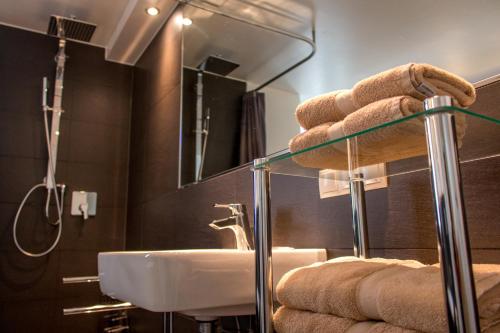 a bathroom with a sink and towels on a shelf at Ferienapartments Am Steinfelder Hof in Bad Neuenahr-Ahrweiler