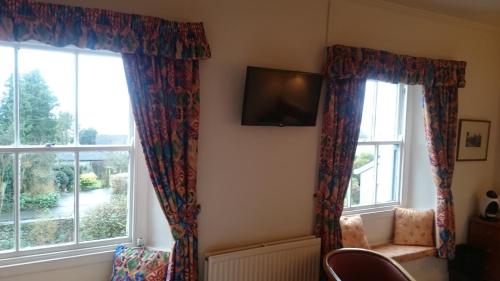 a room with two windows with curtains and a tv at The Silverdale Hotel in Silverdale