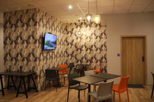 um restaurante com mesas e cadeiras e uma televisão na parede em Hostel City Center Gdynia em Gdynia