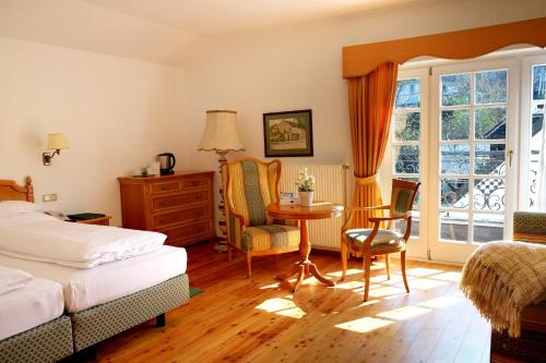 a bedroom with a bed, chair, desk and a window at Hotel Landhaus Fuhrgassl-Huber in Vienna