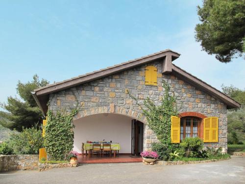 Casa de piedra con persianas amarillas y mesa en Villa Fior di Lavanda, en Cisano sul Neva