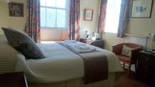 a bedroom with a bed and a chair and a window at The Silverdale Hotel in Silverdale