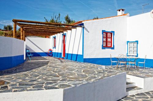 eine Terrasse mit Stühlen und ein Gebäude in Blau und Weiß in der Unterkunft Casa da Eira in Reguengos de Monsaraz