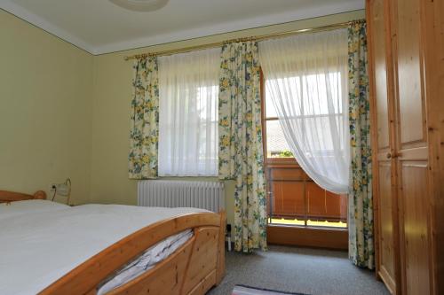 a bedroom with a bed and a window with curtains at Gästehaus Macheiner in Lessach Oberdorf