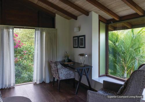 a room with a table and chairs and windows at The Serai Bandipur in Bandipūr