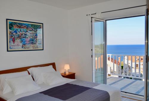 a bedroom with a bed and a balcony with a view at Indigo Cavtat Apartments in Cavtat