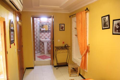 a bathroom with yellow walls and a sink in a room at Maison d'hôtes Dar El Nath in Ouarzazate