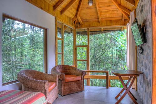 a room with two chairs and a table and windows at Terrabambu Lodge in Mindo