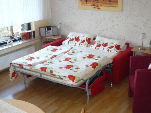a bed in a living room with a red couch at Ferienwohnung Kleinschmidt in Heimbach