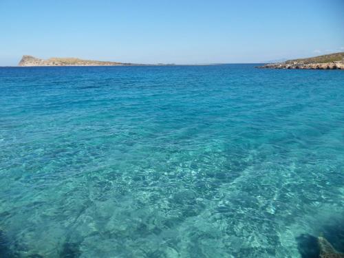 a large body of clear blue water with an island at Elounda Island Villas in Elounda