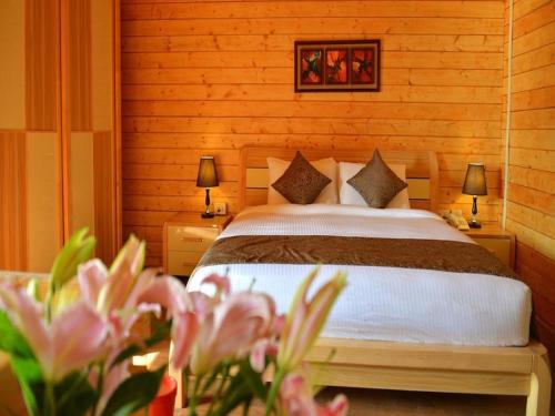ein Schlafzimmer mit einem Bett, zwei Lampen und Blumen in der Unterkunft Orabella Villas & Suites in Calangute