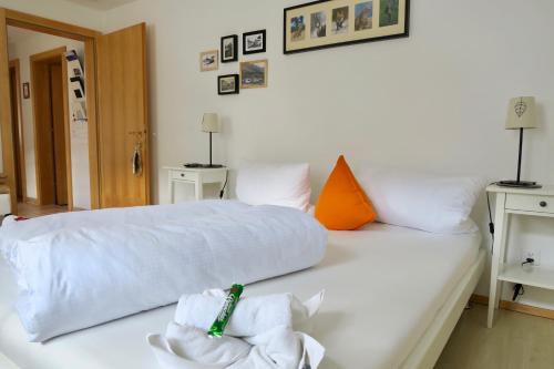 a white bed with white sheets and orange pillows at Apartment MEZPRA in Samnaun