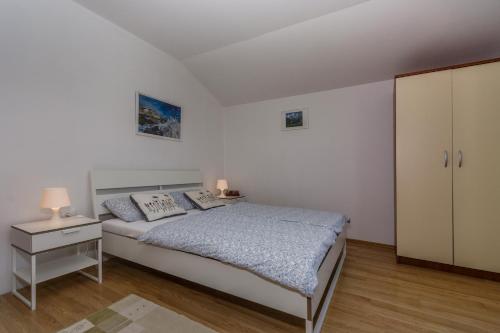 a white bedroom with a bed and a cabinet at Apartments Ana in Novigrad Istria