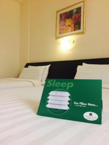 a sign on a bed in a hotel room at Hotel Al Madinah Holiday in Muscat