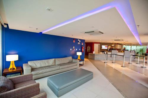 a living room with a couch and a blue wall at Go Inn Hotel Aracaju in Aracaju