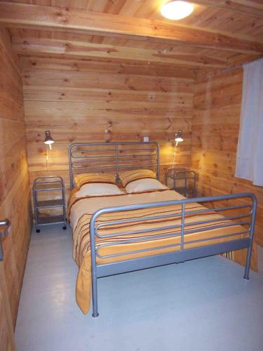 - une chambre avec un lit en métal dans une cabane en rondins dans l'établissement Albaria Lodge, à Saint-Florent