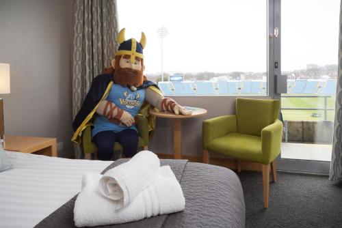 a room with a mascot sitting in a chair next to a bed at Headingley Lodge in Leeds