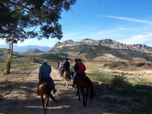 a group of people riding horses down a dirt road at Albaria Lodge in Saint-Florent