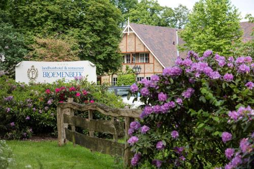 een tuin met bloemen en een hek voor een gebouw bij Landhuishotel De Bloemenbeek in De Lutte