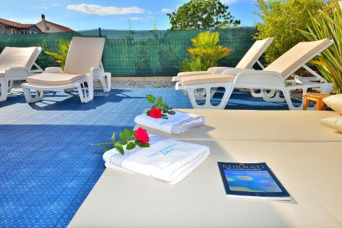 a patio with lounge chairs and towels on a table at Villa Dalmatina Zadar mit Pool in Zadar
