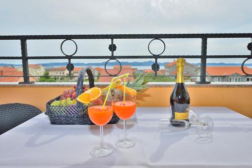 a table with two glasses of orange juice and a basket of fruit at Villa Dalmatina Zadar mit Pool in Zadar