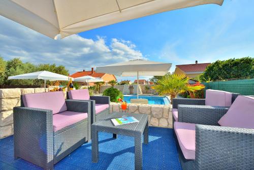 a patio with chairs and an umbrella and a pool at Villa Dalmatina Zadar mit Pool in Zadar