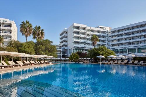阿依納帕的住宿－古希臘灣酒店，一个带椅子和遮阳伞的大型游泳池