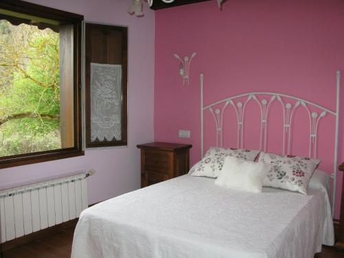 a bedroom with a white bed with pink walls at Casa Leny in La Vega