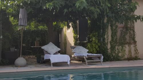 two chairs and a table next to a swimming pool at "Le Vent d'Étoile" B&B and Guesthouses in Mormoiron