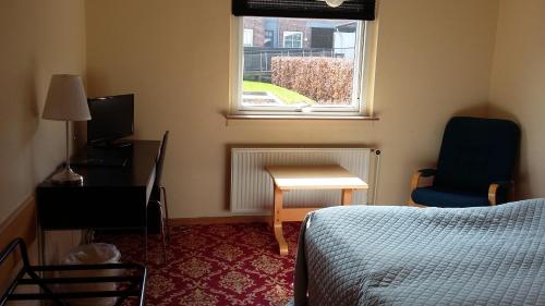 Schlafzimmer mit einem Bett, einem Schreibtisch und einem Fenster in der Unterkunft Hotel Kong Valdemar in Vordingborg