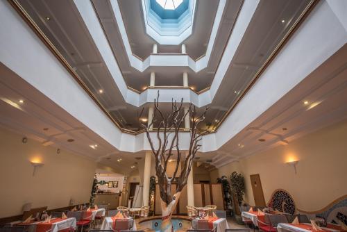 a lobby with a ceiling with a tree in the middle at Hotel Kalma, Kalma Villa, Apart Hotel in Hévíz