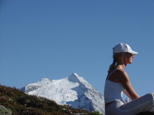 a woman sitting on a hill looking at a mountain at Boutique Appartments Gerlosperle in Gerlos