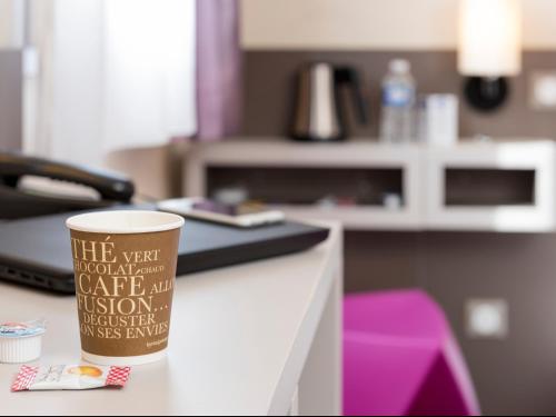 a coffee cup sitting on top of a counter at Kyriad Hotel Lyon Givors in Givors