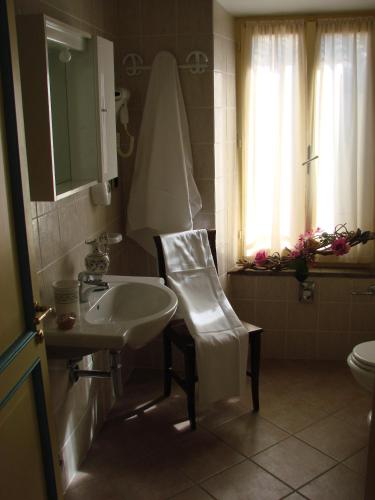 a bathroom with a sink and a chair and a mirror at Hotel Palazzo Brunamonti in Bevagna