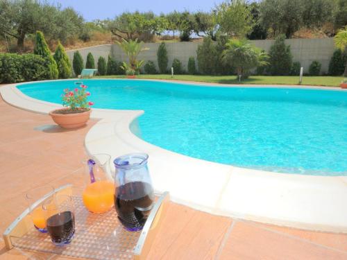 a table with glasses of orange juice next to a swimming pool at Belvilla by OYO Villa Rita in Buseto Palizzolo