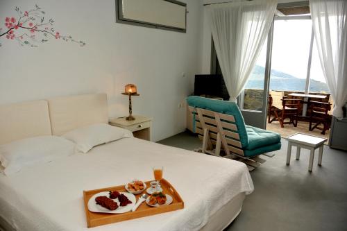 Una habitación de hotel con una cama con una bandeja de comida. en Celini Suites Hotel, en Marmarion