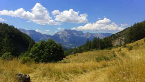 a grassy hill with mountains in the background at La Collinette in Saint-Laurent-du-Cros