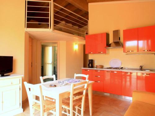 kuchnia z czerwonymi szafkami oraz białym stołem i krzesłami w obiekcie Belvilla by OYO Cozy Holiday Home with barbecue w mieście Polpenazze del Garda