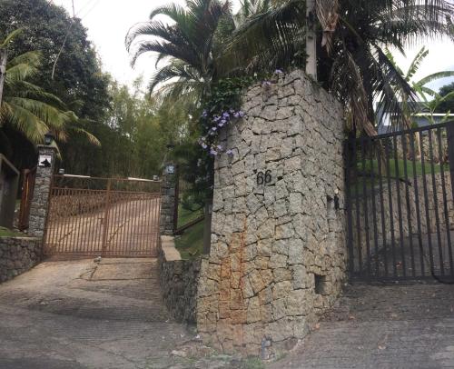 a stone wall with flowers on it next to a fence at Casa Yacht Club in Ilhabela