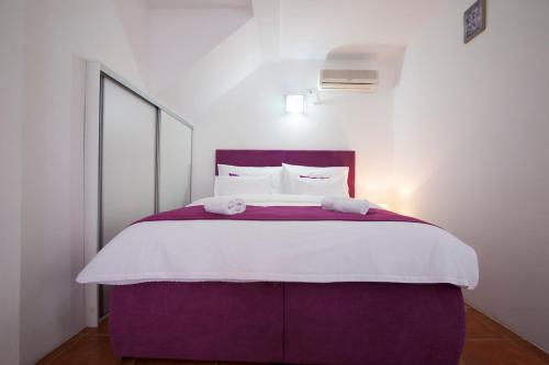 a bedroom with a large purple bed with white pillows at Apartments Grand in Sveti Stefan