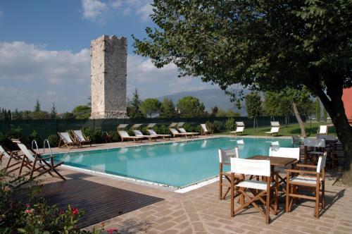 a pool with chairs and a table and a tower at Residenza Torre Acquatino in Spello