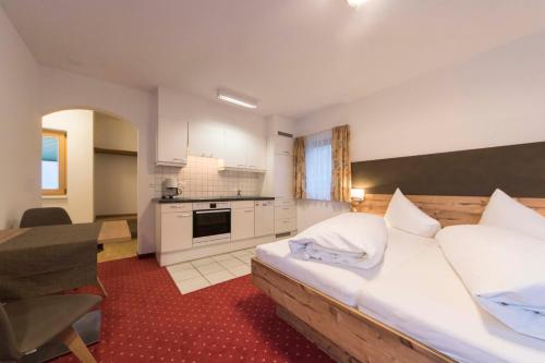 a bedroom with a large bed and a kitchen at Appartements Garni Alpin Live in Samnaun