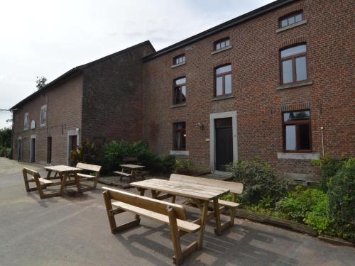 three picnic tables in front of a brick building at Spacious holiday home in Teuven with garden in Teuven