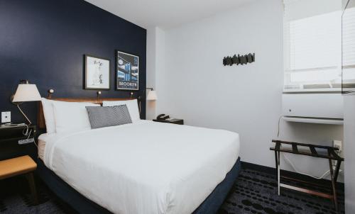 a bedroom with a white bed and a blue wall at U Hotel Fifth Avenue, Empire State Building in New York